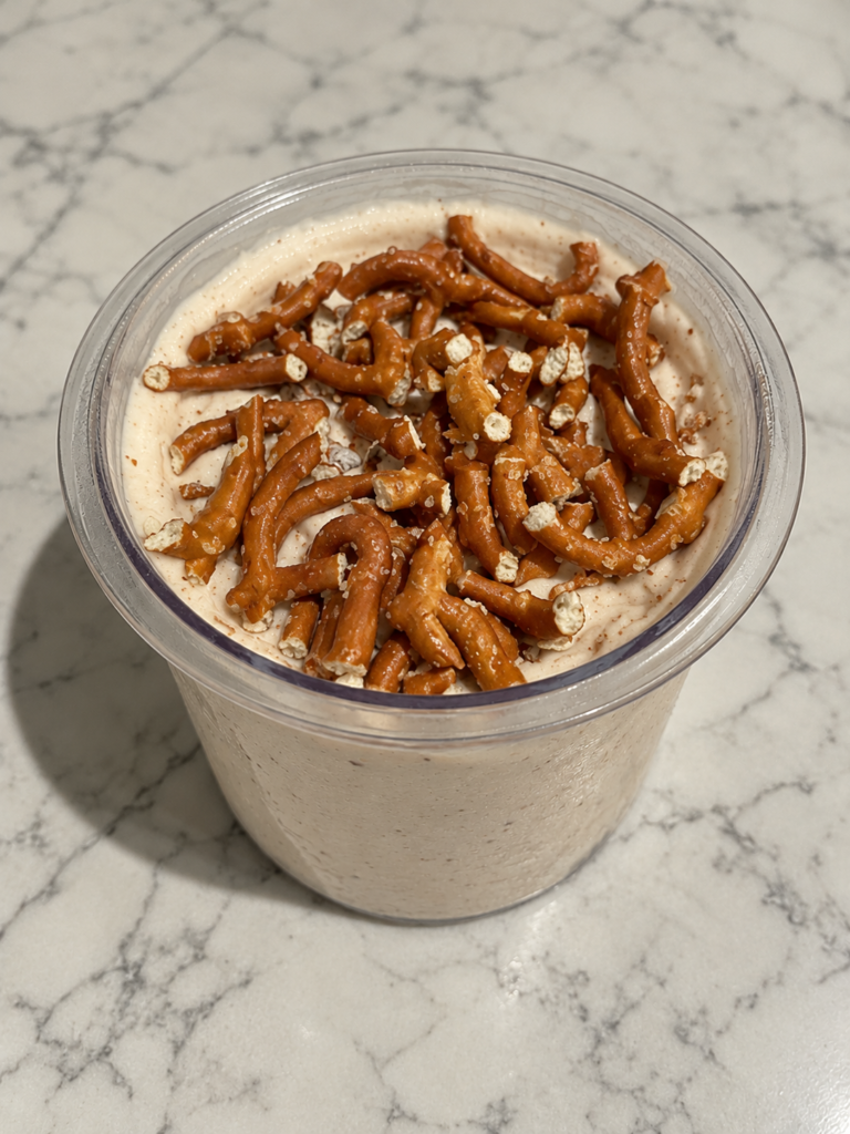 High-Protein Peanut Butter Ninja Creami topped with crushed pretzels in a Ninja Creami pint container.