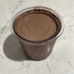 High-Protein Chocolate Cookie Blast Ninja Creami in a pint container with a smooth, creamy chocolate-cookie surface.