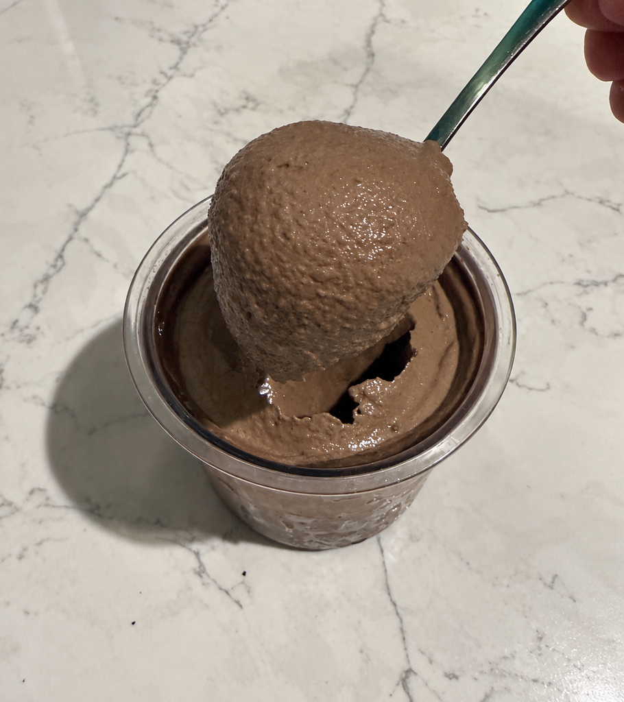Spoon lifting a thick, creamy scoop of High-Protein Chocolate Cookie Blast Ninja Creami from the pint.