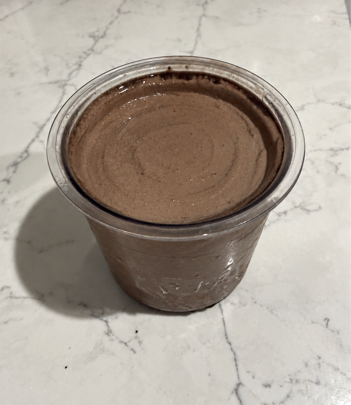 High-Protein Chocolate Cookie Blast Ninja Creami in a pint container with a smooth, creamy chocolate-cookie surface.