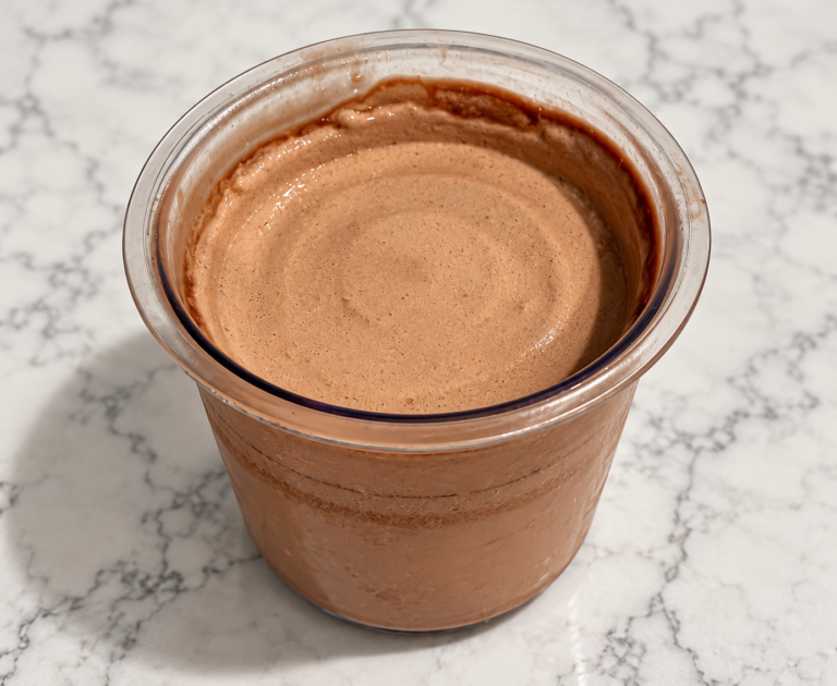 High-Protein Chocolate Pudding Ninja Creami in a clear pint container with a smooth, creamy chocolate surface
