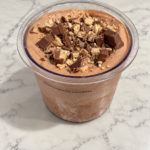 High-Protein Kit Kat Chocolate Ninja Creami topped with chopped Kit Kat pieces in a Ninja Creami pint.
