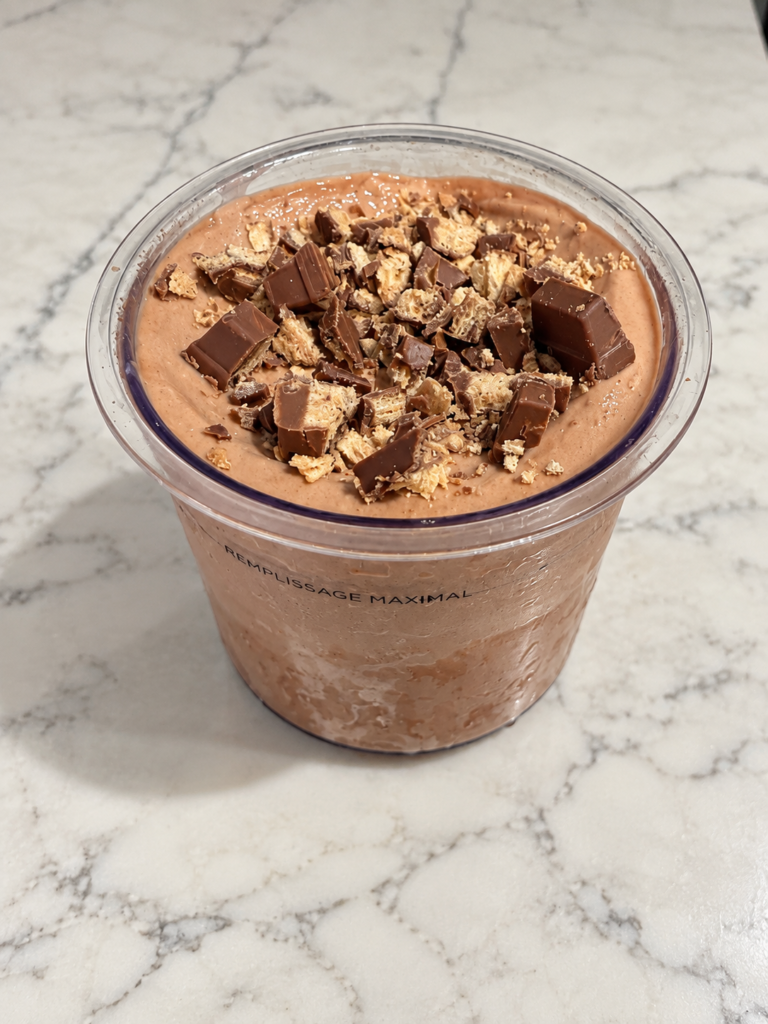 High-Protein Kit Kat Chocolate Ninja Creami topped with chopped Kit Kat pieces in a Ninja Creami pint.
