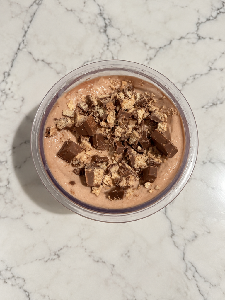Top-down view of High-Protein Kit Kat Chocolate Ninja Creami with chopped chocolate-covered wafer pieces on top.