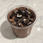 High-Protein Oreo Chocolate Cookie Blast Ninja Creami topped with crushed Oreo Thins in a Ninja Creami pint