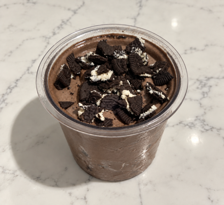High-Protein Oreo Chocolate Cookie Blast Ninja Creami topped with crushed Oreo Thins in a Ninja Creami pint