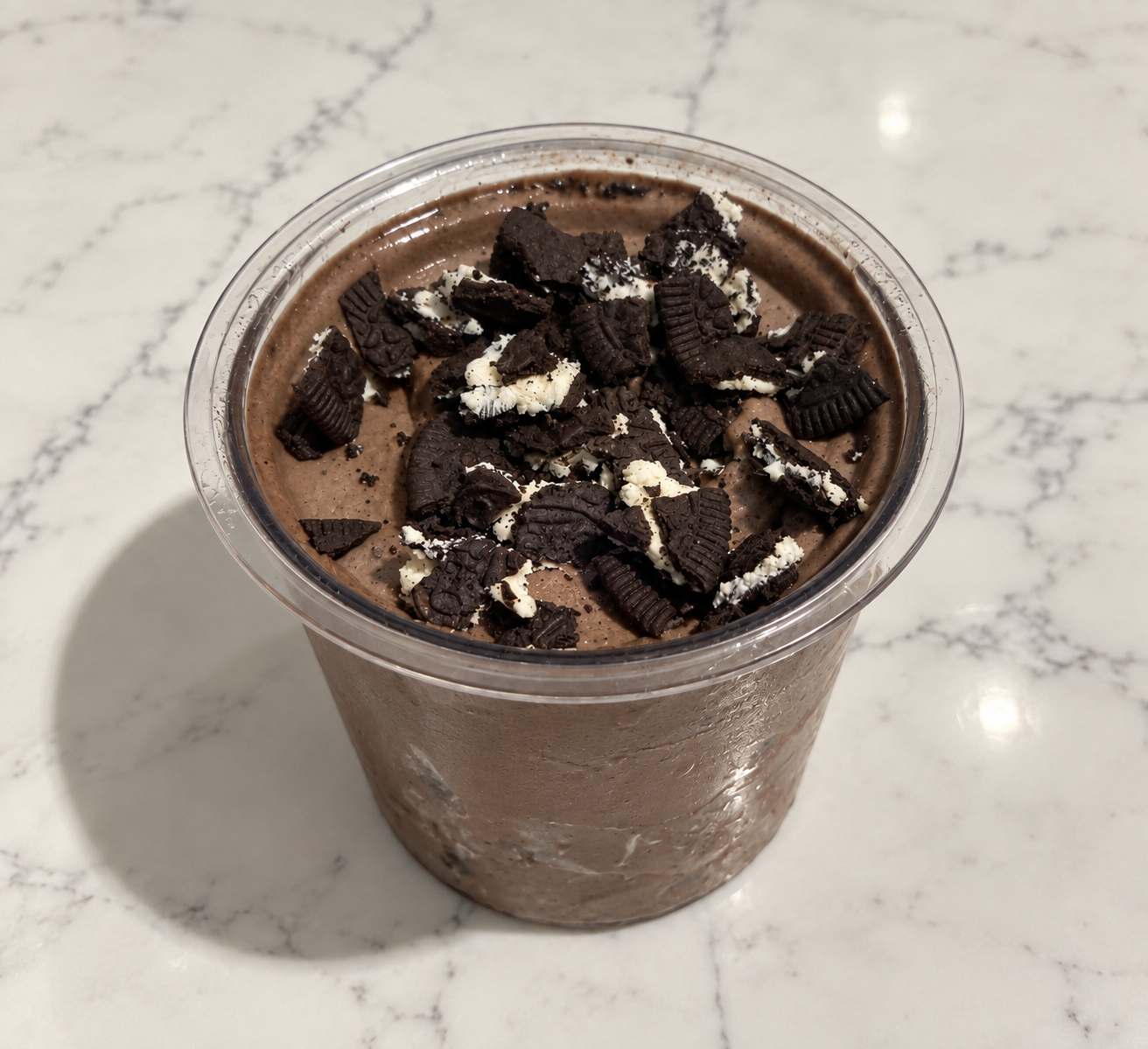 High-Protein Oreo Chocolate Cookie Blast Ninja Creami topped with crushed Oreo Thins in a Ninja Creami pint