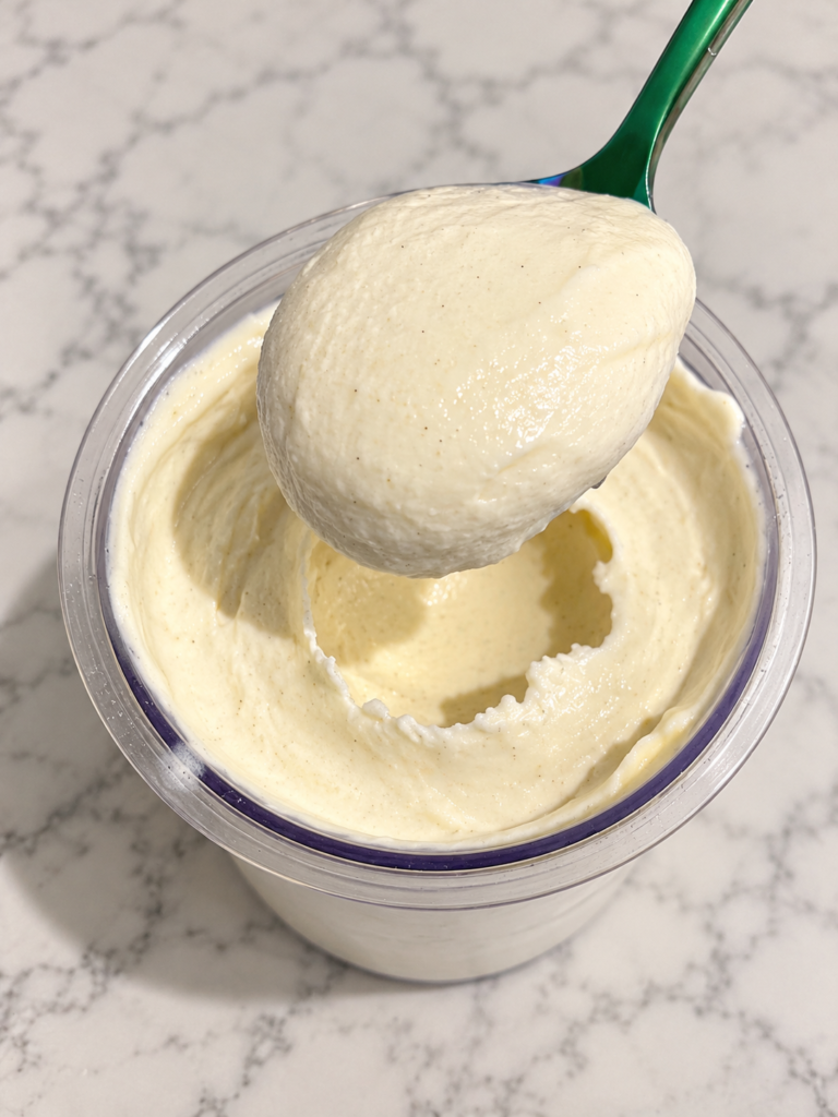 Green spoon lifting a thick, creamy scoop of High-Protein Vanilla Pudding Ninja Creami