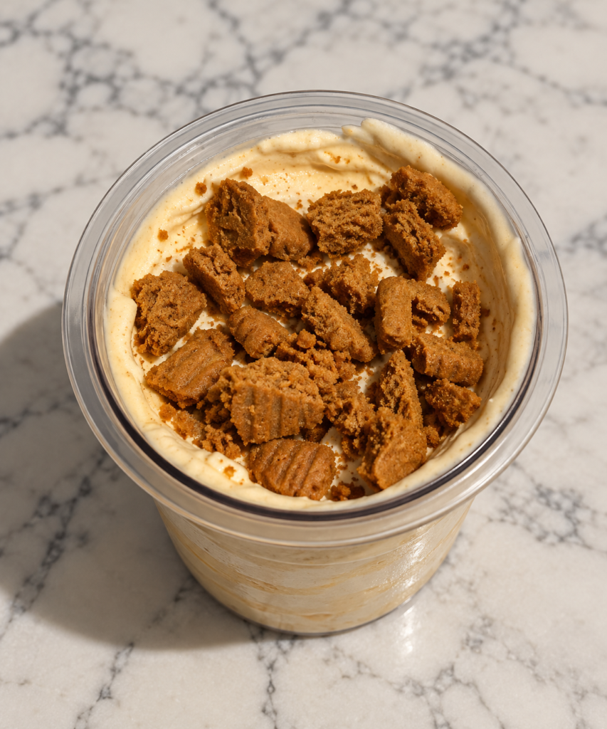 Creamy butterscotch Ninja Creami ice cream topped with two crumbled Lotus Biscoff cookies in a clear pint container.