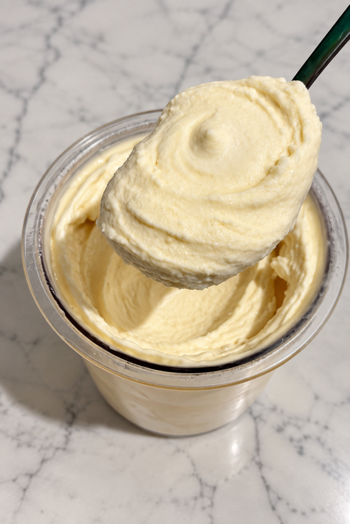 Green spoon lifting a thick scoop of high-protein strawberry shortcake Ninja Creami